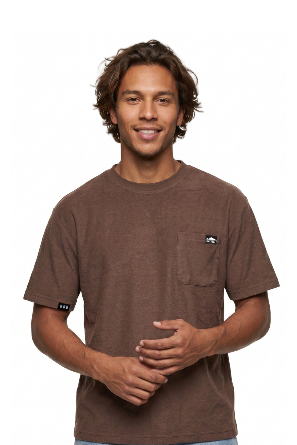 Man wearing a brown t-shirt with a chest pocket  a small logo bagde on a white background