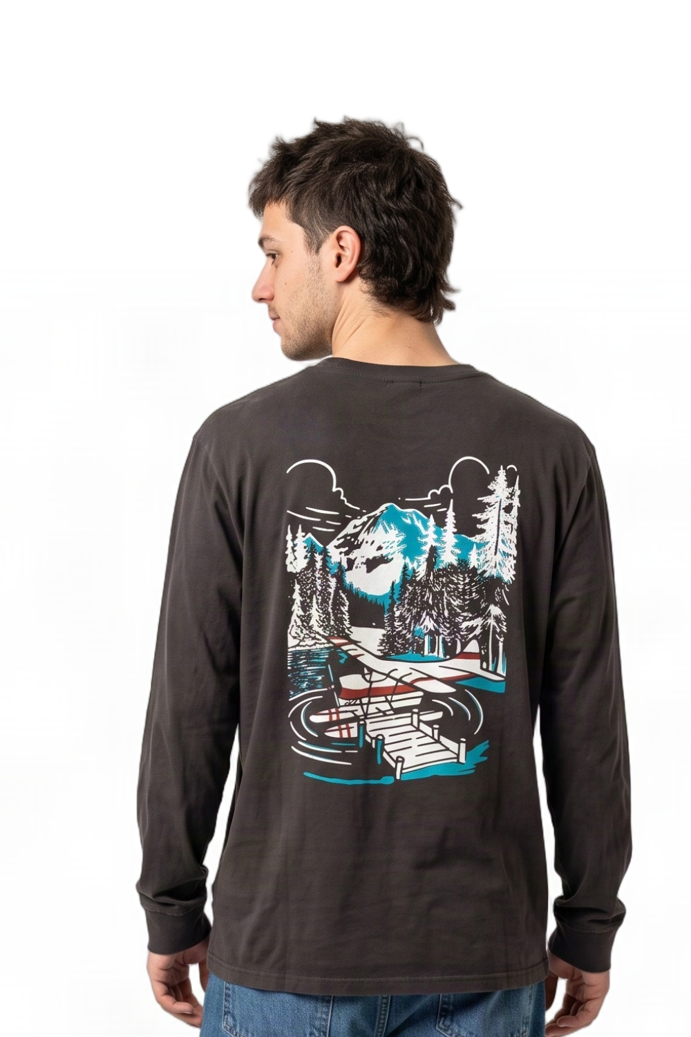 A man wearing a olive black long-sleeve t-shirt, viewed from the back. The shirt features a large graphic print on the back depicting a mountain, pine trees, and a cabin by a lake in white, blue, and black.